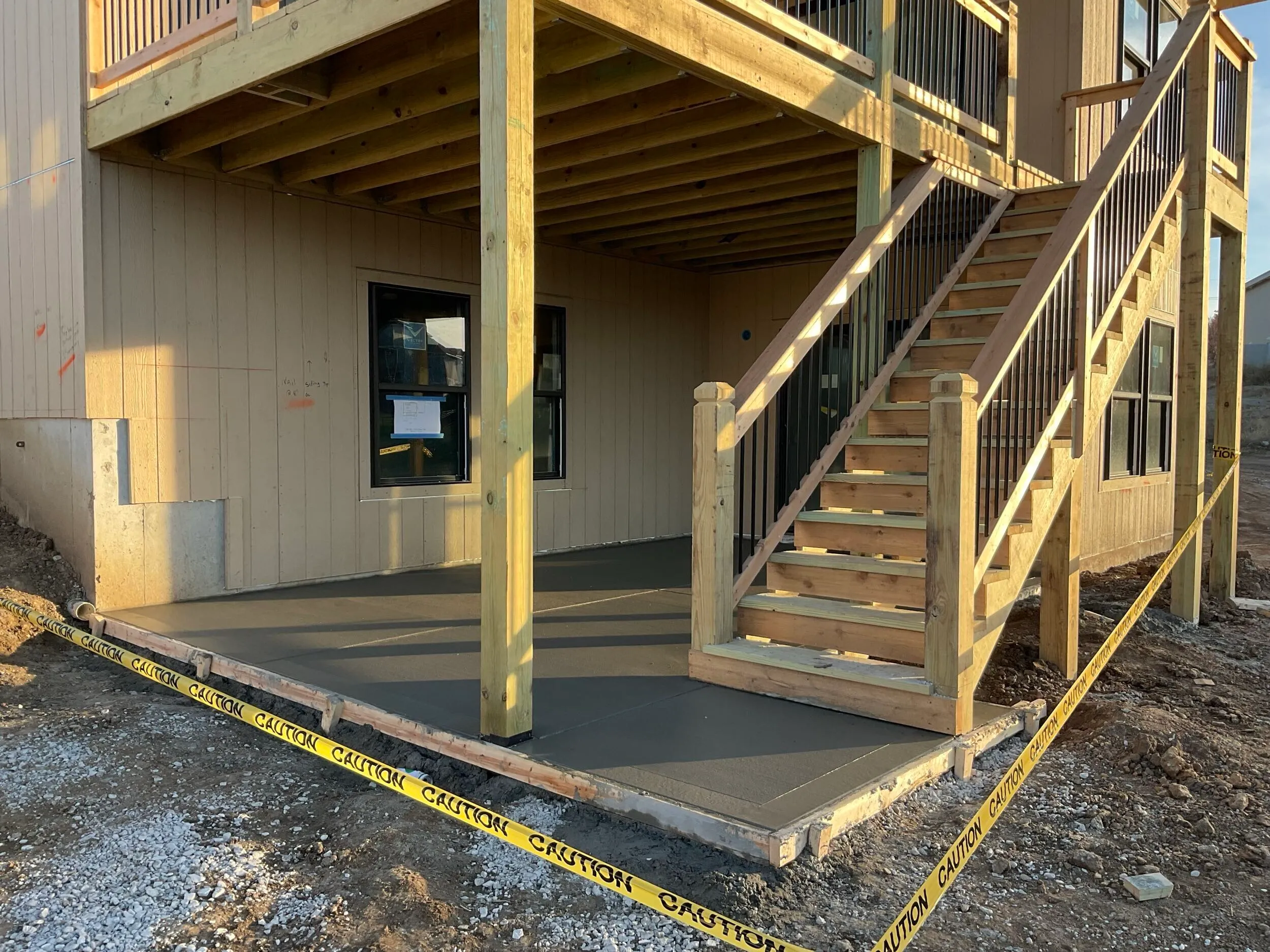 Concrete patio poured under a covered deck with a fresh broom finish