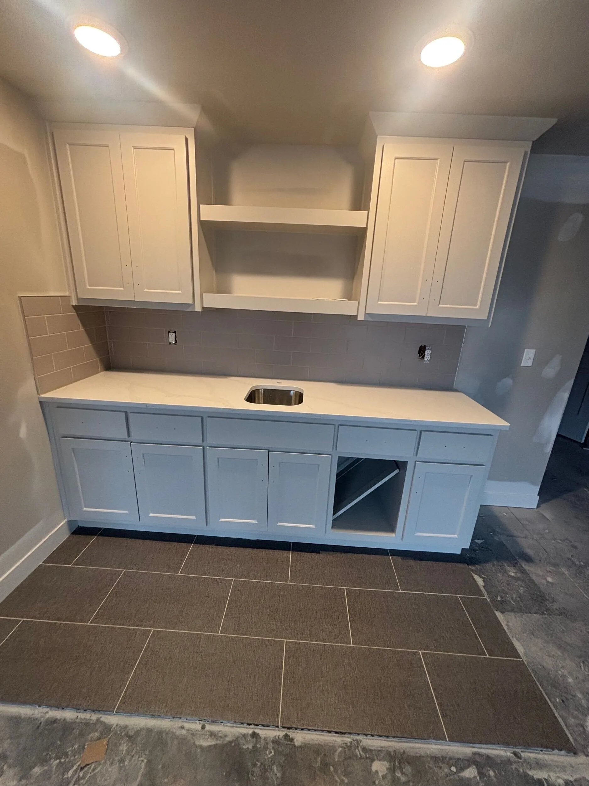 White shaker bar cabinet with quartz top, subway tile backsplash, and tile floor